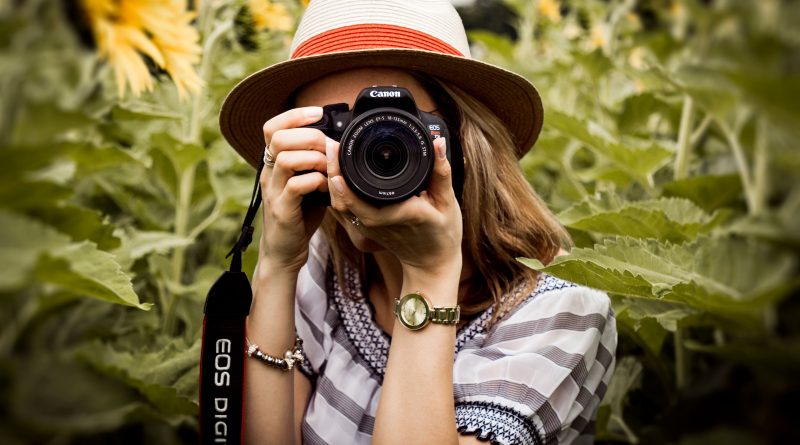 Photographer holding a DSLR camera in a sunflower field